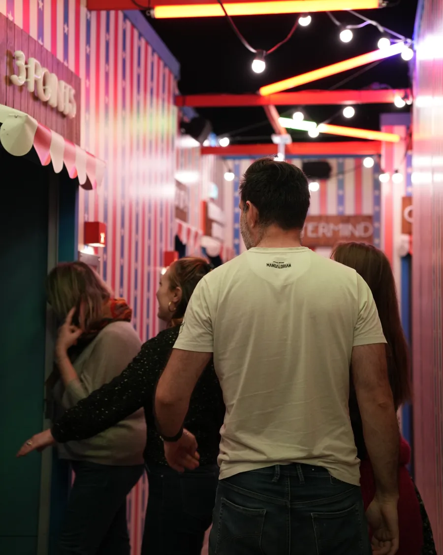 Des joueuses et des joueurs dans l'allée éclairée, entre deux stands